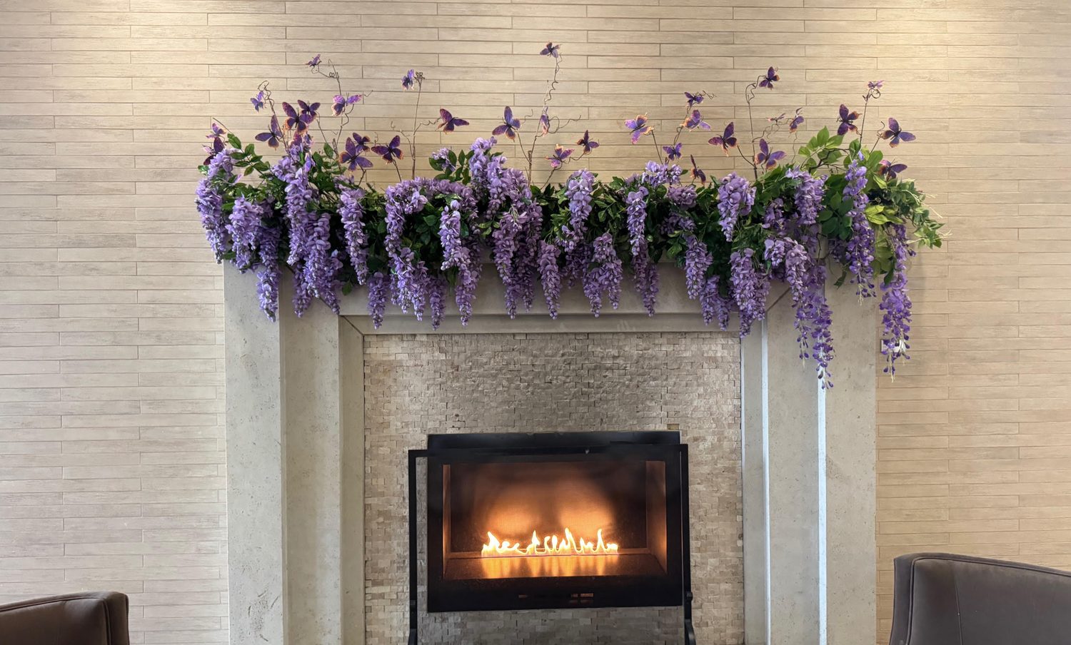 Wisteria and butterfly mantel garland over a lobby fireplace