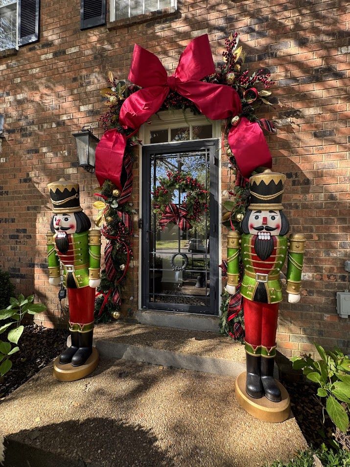 Residential front door with nutcrackers and a red bow garland