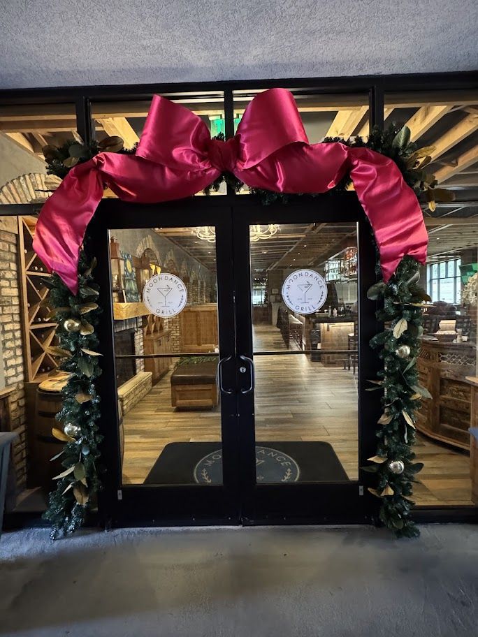 Grand red bow and garland framing restaurant entrance doors