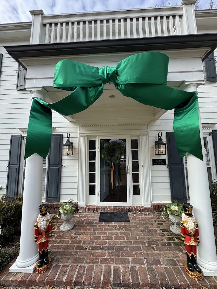 White columned porch wrapped with a large green bow and nutcrackers