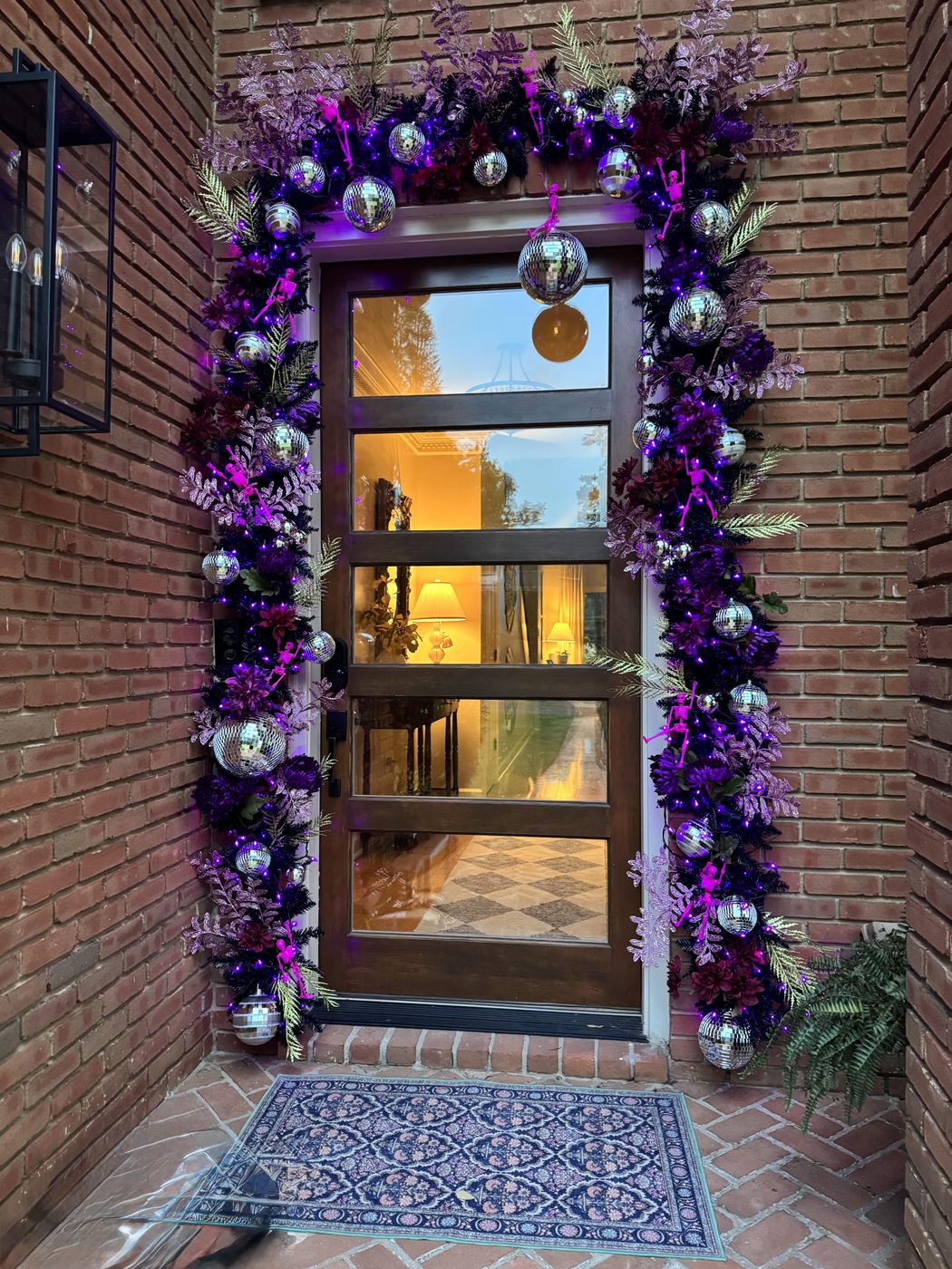 Halloween front door arch with purple garland, disco balls and skeletons