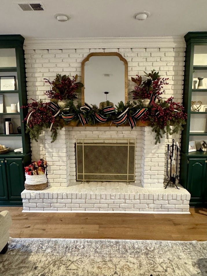 Red berry and magnolia Christmas garland on a white-brick mantel