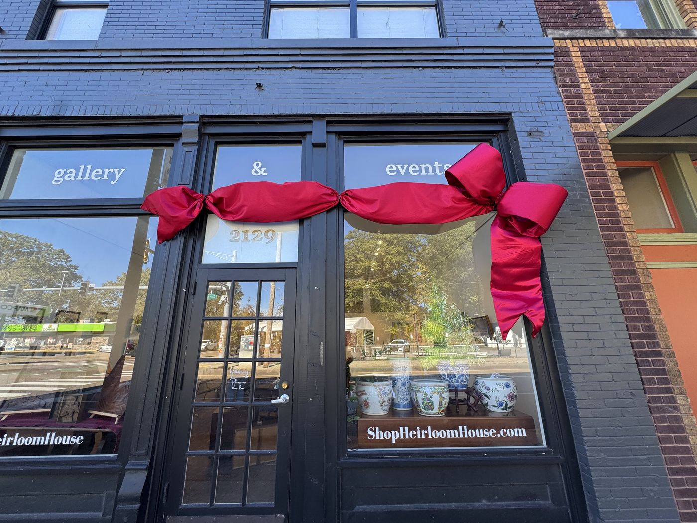 Black storefront windows wrapped with a red holiday ribbon and bow